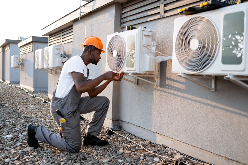 A technician performing maintenance on air conditioning units on a rooftop to ensure proper cooling performance.