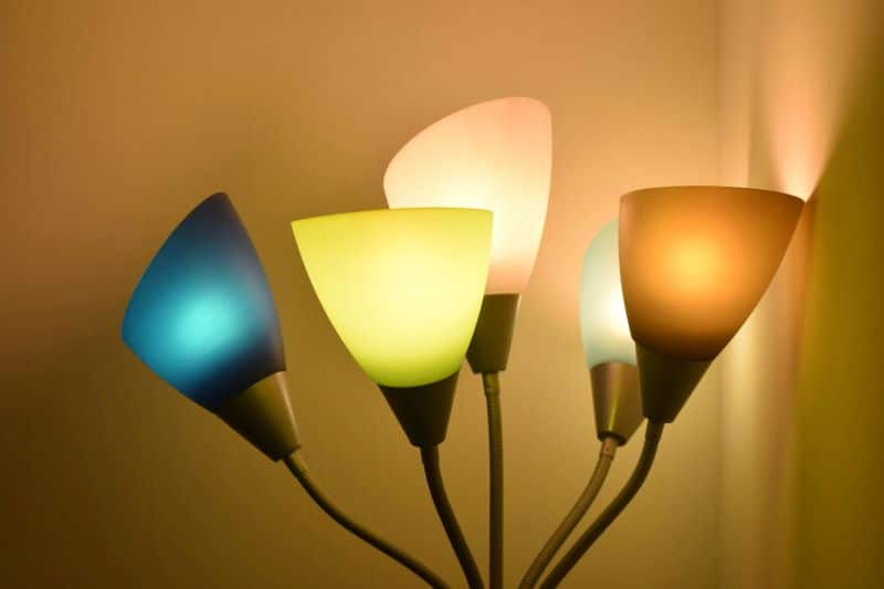 A set of colorful table lamps with different shades illuminating a warm-toned wall.