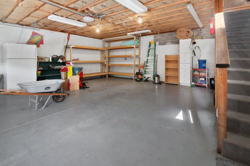 Spacious garage with shelves, basic storage, and minimal furnishings, offering potential for a garage renovation makeover.
