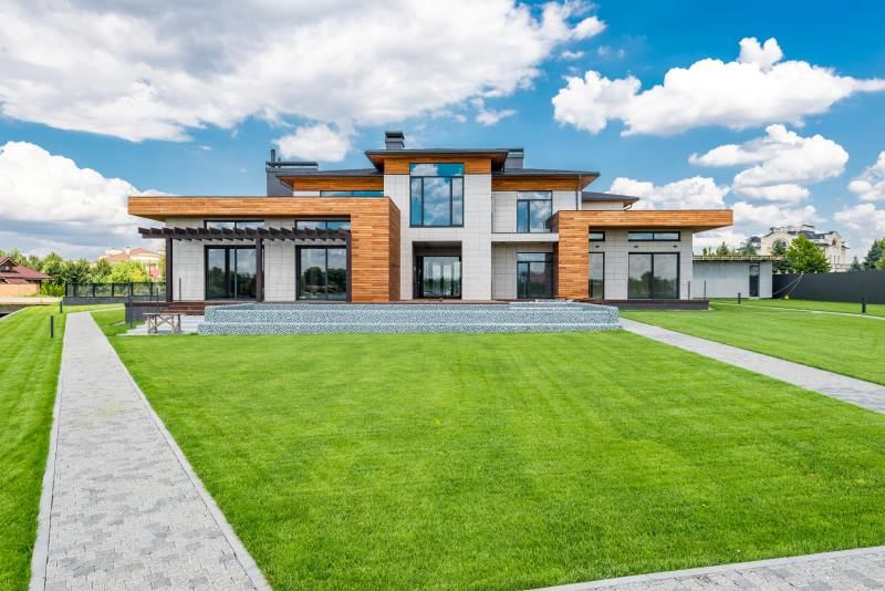 Modern luxury home with expansive lawn and sleek architectural design, showcasing high-end property features.