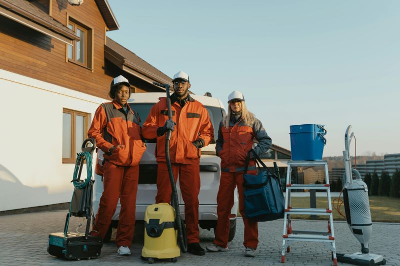 Team of three workers standing in front of a vehicle with cleaning equipment, ready to provide air duct cleaning services.