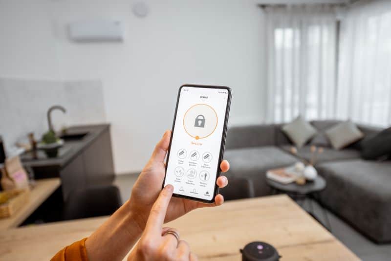 A person using a smartphone to control home security system with a lock icon displayed on the screen.