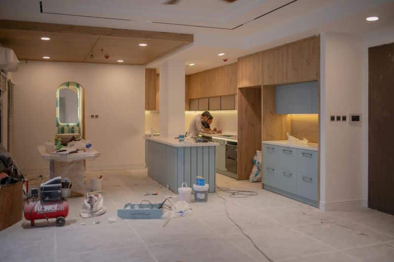 A worker carrying out major repairs in a kitchen, renovating the space before selling the property.
