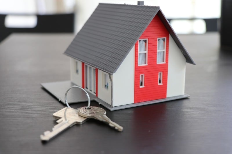 Model house with keys on a table, symbolizing home security measures to prevent future issues after a break-in.