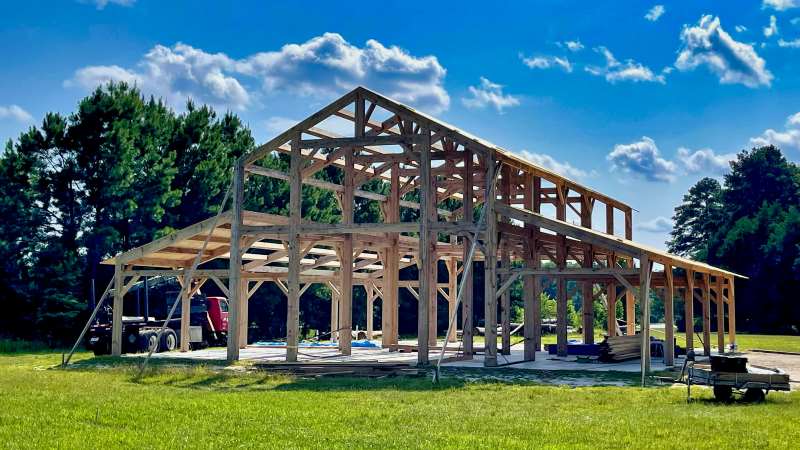 A construction site showing the framework of a building under construction, showcasing the use of prefabrication with pre-assembled wooden beams and structural components.