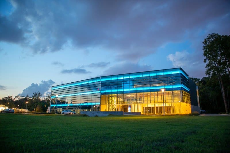Modern glass smart building illuminated at dusk, showcasing architectural design and integrated security solutions features.