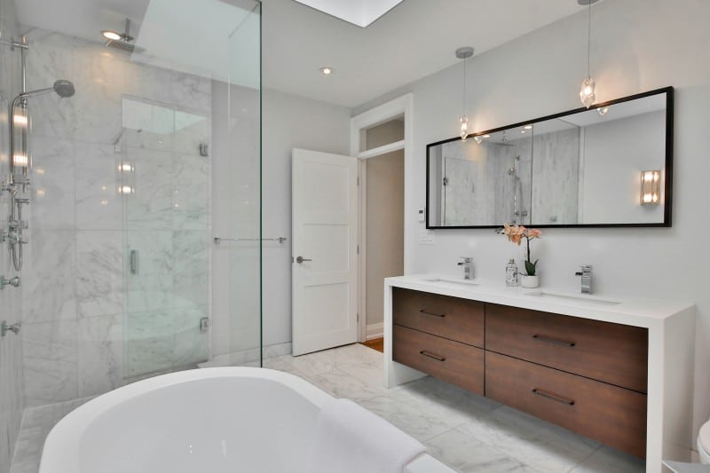 Bathroom.jpg: Modern bathroom with glass shower, double vanity with wooden drawers, large mirror, and freestanding tub in a bright marble-finished bathroom.