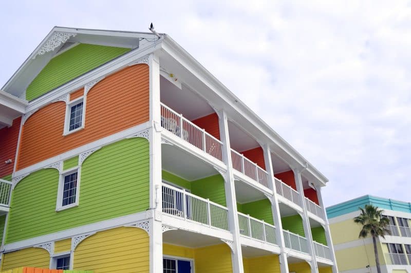 Colorful vacation rental building with bright green, yellow, and orange walls, white balconies, and decorative trim showing how modern tools support property management.