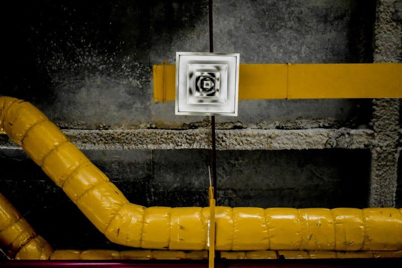 Yellow insulated air duct system on a ceiling, highlighting potential areas where subtle air leaks can raise utility bills due to inefficient sealing.