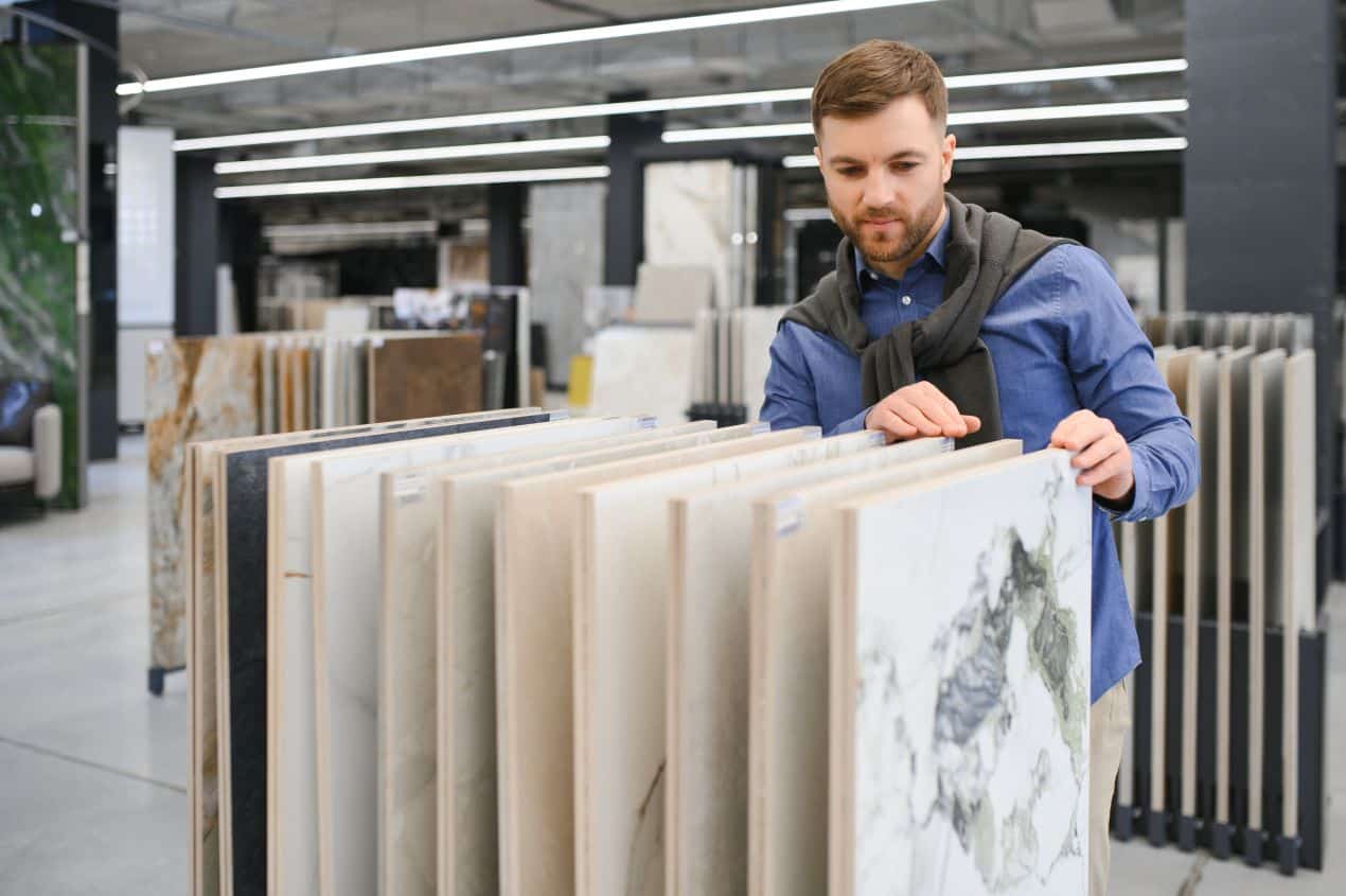 Man examining large marble slab samples in a showroom display.