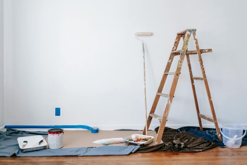 Painting setup with ladder, roller, and tools against a white wall—showing simple design tricks to refresh a home.