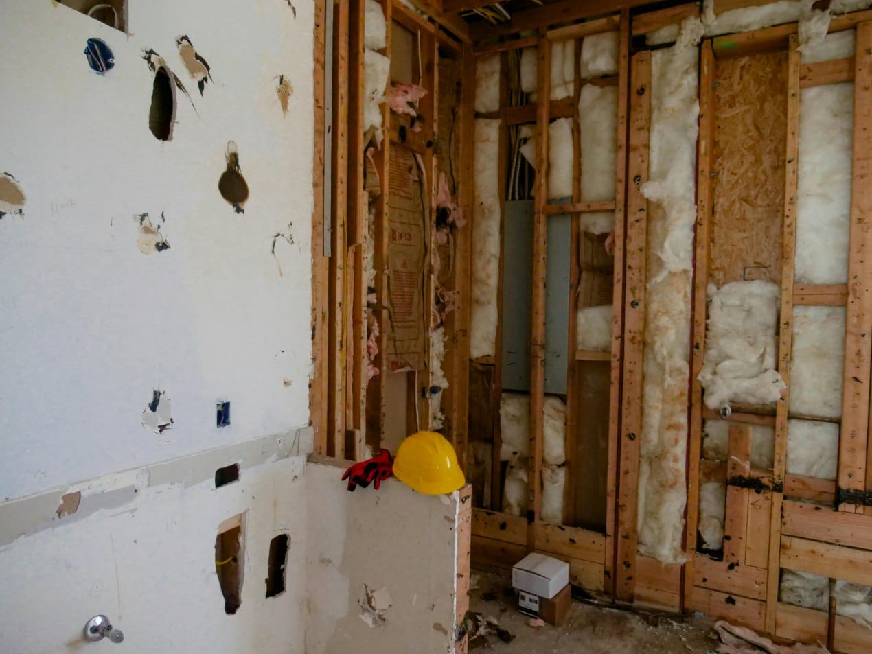 Partially demolished room showing exposed studs and insulation during renovation.