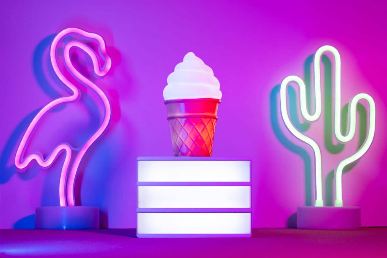 Vibrant pink and green neon signs shaped like a flamingo and cactus with an illuminated ice cream cone display, symbolizing creative storefront design that attracts customers.