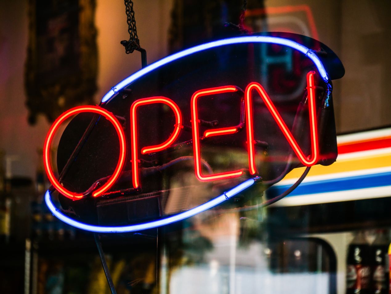 Bright red and blue open neon sign glowing in a shop window, representing how neon signage increases visibility and customer engagement for retail businesses.