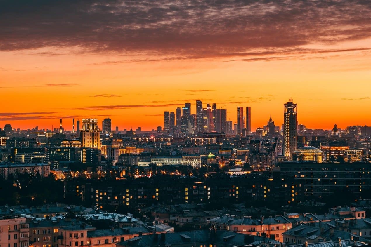 City skyline at sunset with tall modern skyscrapers and older buildings in the foreground, illustrating an urban living solution that balances density and livability.