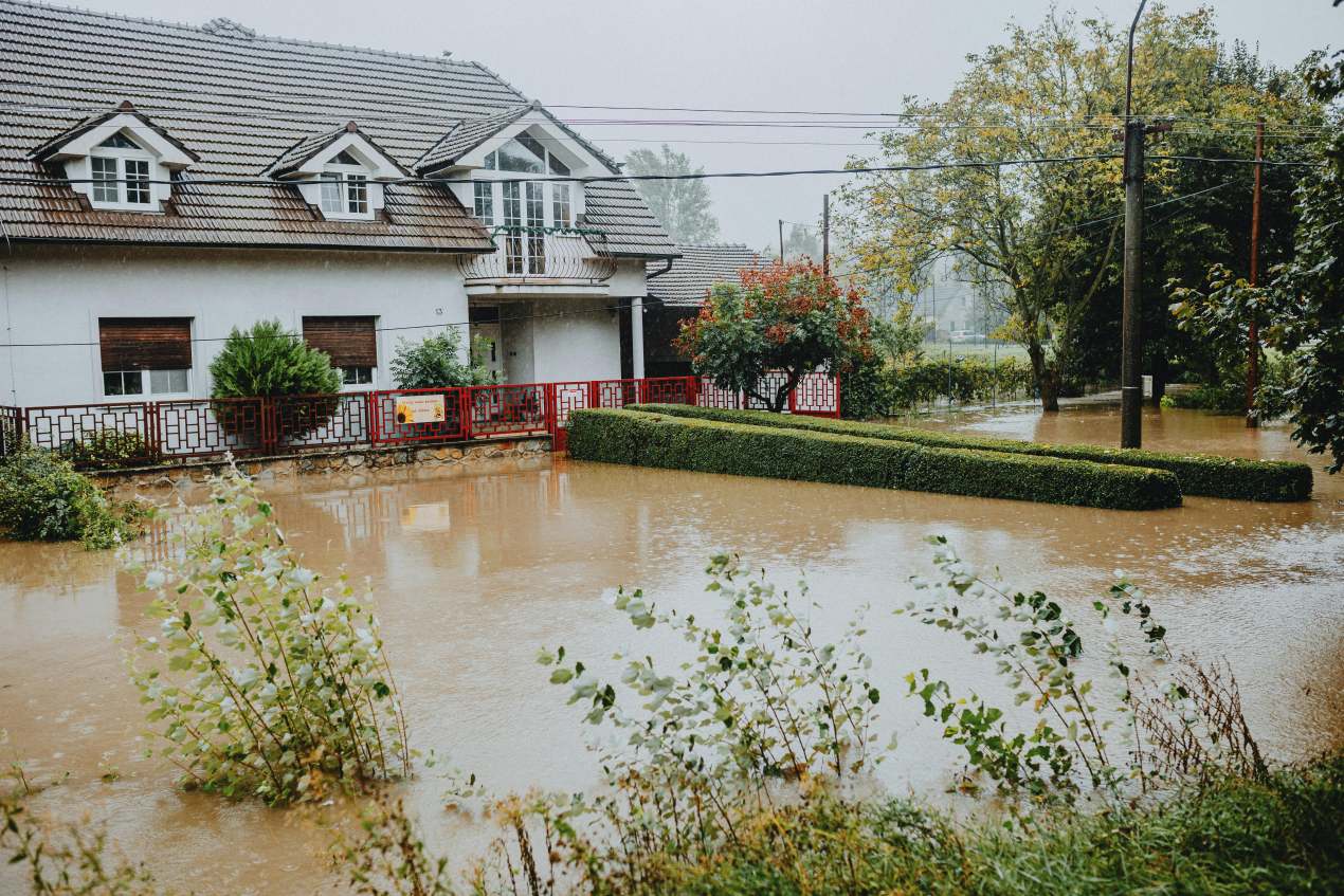 Flooded residential home with standing water surrounding the property after heavy rainfall, highlighting climate and homes risks and the need for fast action to prevent water damage.