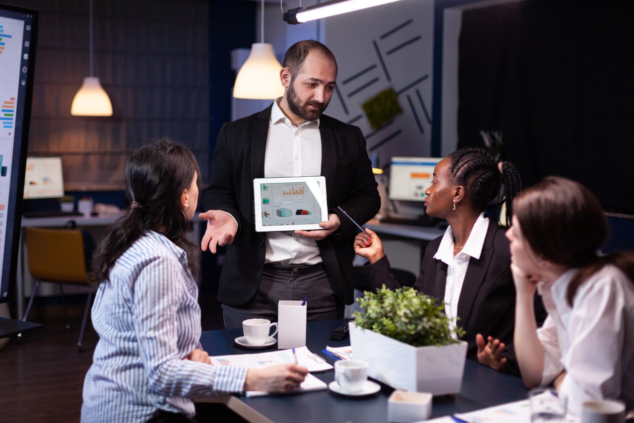 – A business professional presents startup performance charts on a tablet to a diverse team during a collaborative meeting, illustrating practical guidance and strategy discussion for business startups in Australia.