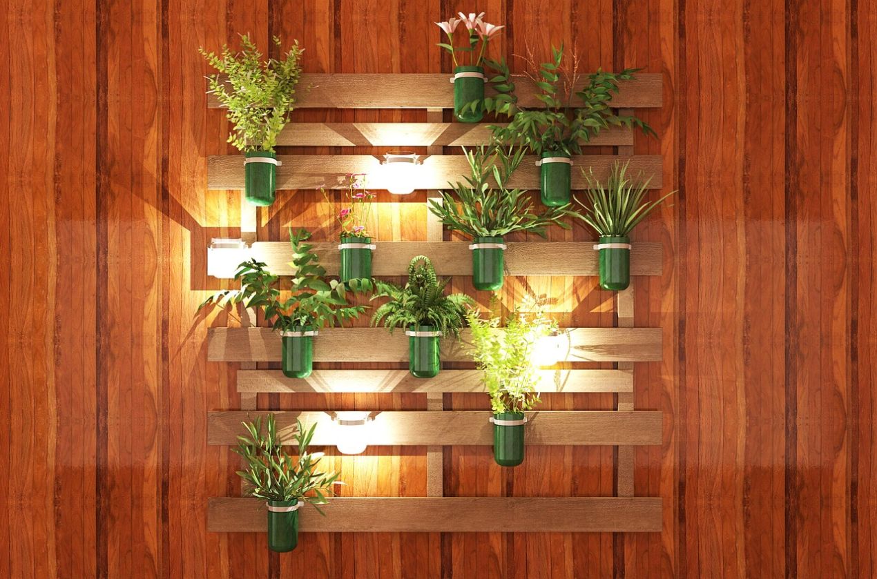 Vertical wooden wall finish wall with mounted pallet-style shelves holding green potted plants and warm wall lights, creating a modern decorative interior accent.