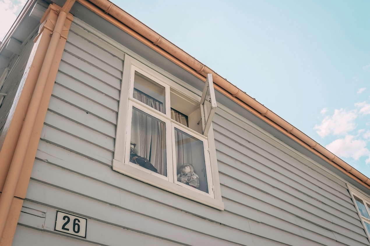 Older home exterior with open window showing when to Replace Windows before selling to improve curb appeal and buyer confidence.
